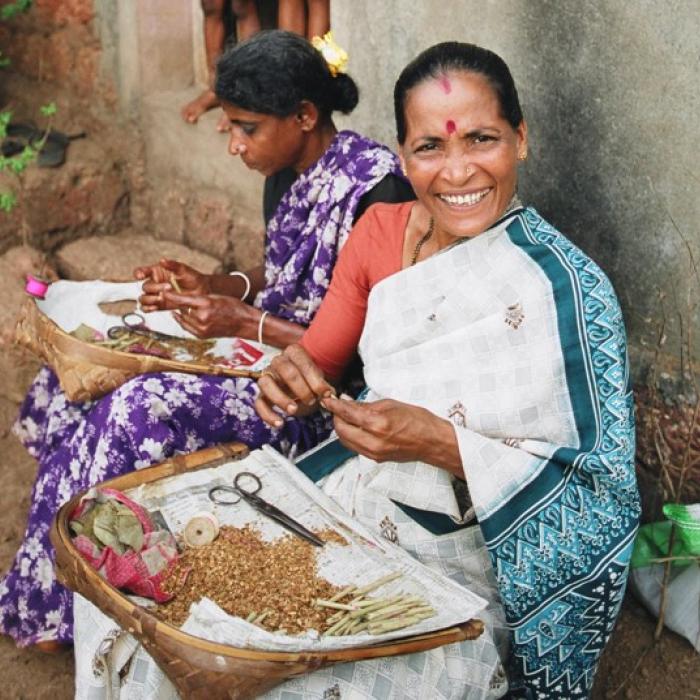 Two Indian women sitting outdoors while working.